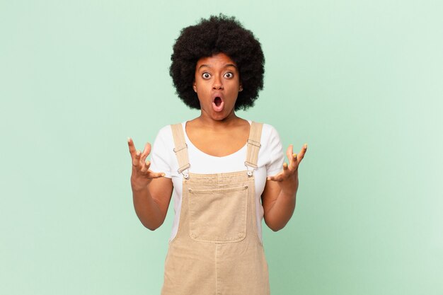 Afro woman open-mouthed and amazed, shocked and astonished with an unbelievable surprise chef concept