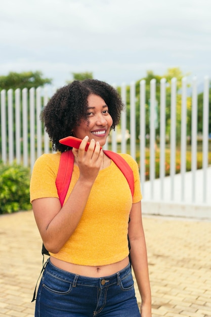 Афро-женщина отправляет голосовое сообщение по мобильному телефону в парке