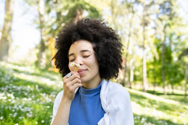 afro woman smelling flowers in the park