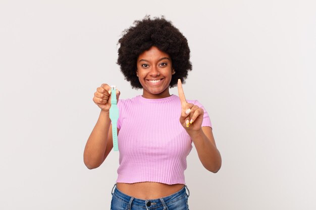 Afro woman smiling proudly and confidently making number one pose triumphantly, feeling like a leader watch concept