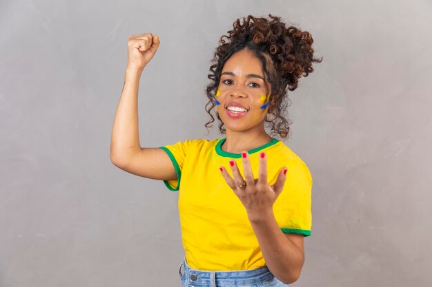 Afro woman supporter of Brazil football championship screaming goal celebrating team victory and goal