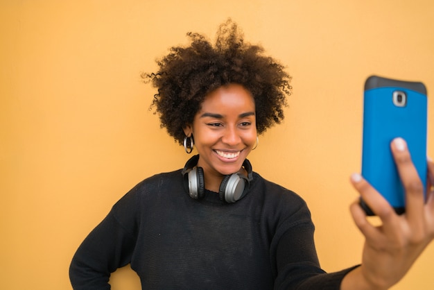 Afro woman taking selfies with phone.