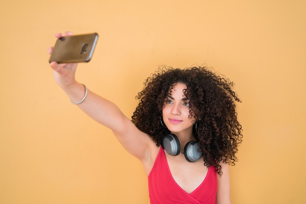 Afro woman taking selfies with phone.