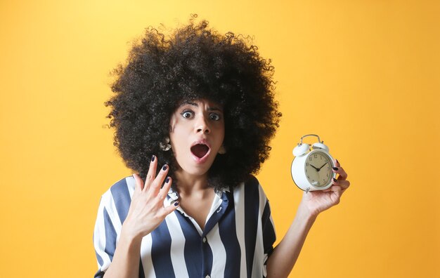 Photo afro woman, with alarm clock and scared face