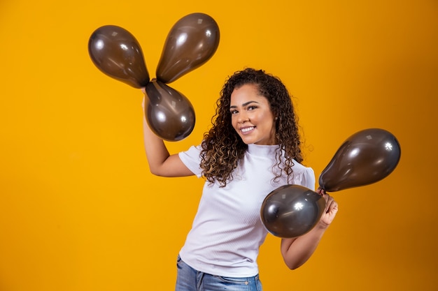 Donna afro con palloncini neri che celebra le offerte di compleanno. saldi del black friday