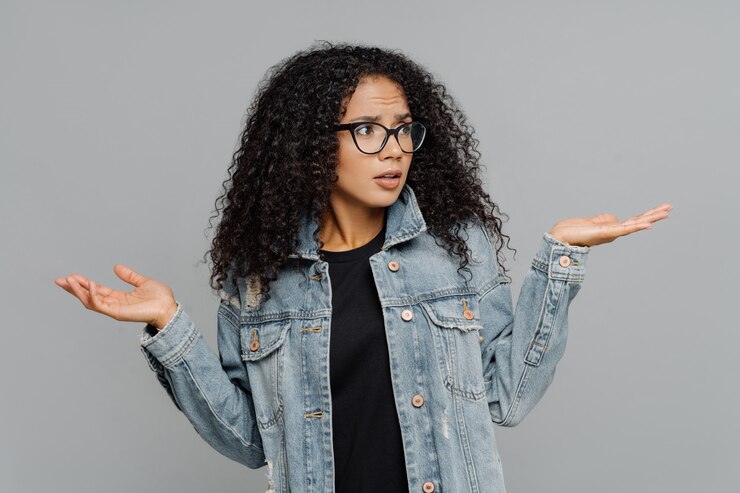 Photo afro woman with crisp hair, raises hands in bewilderment, looks aside