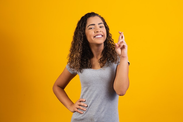 Afro woman with fingers crossed cheering victory