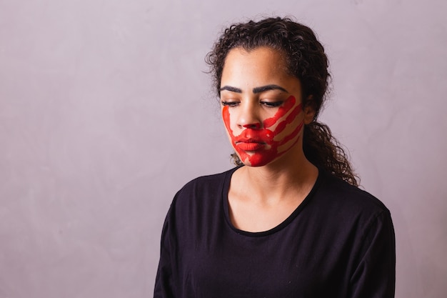 Afro woman with handprint on her mouth in favor of awareness of feminicide. Domestic violence