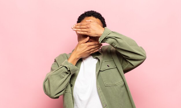 Afro young black woman covering face with both hands saying no to the camera! refusing pictures or forbidding photos