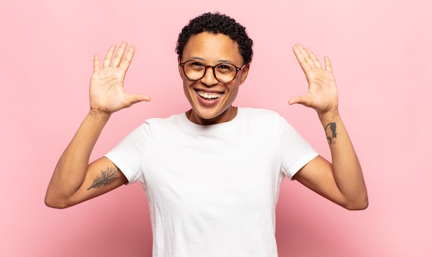 Afro young black woman smiling and looking friendly, showing number ten or tenth with hand forward, counting down