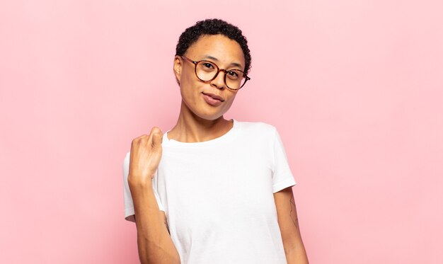 Afro young woman looking arrogant, successful, positive and proud, pointing to self