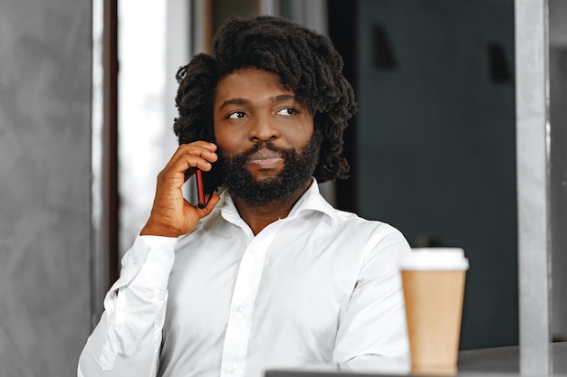 Afro zakenman in wit overhemd praten aan de telefoon close-up