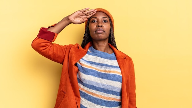 Afro zwarte mooie vrouw die de camera begroet met een militaire groet in een daad van eer en patriottisme, respect tonen