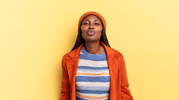 Afro-zwarte mooie vrouw die lippen samendrukt met een schattige, leuke, gelukkige, mooie uitdrukking, een kus sturend