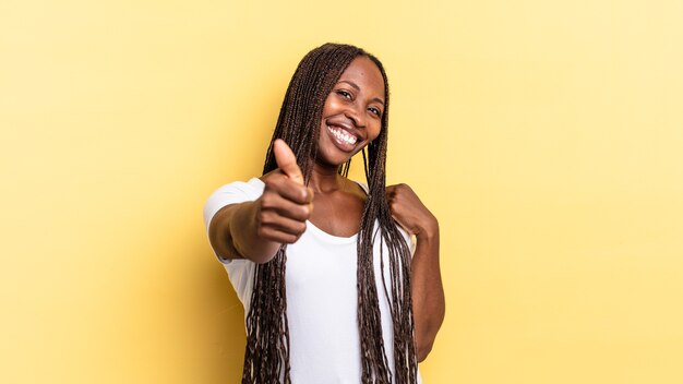 Afro zwarte mooie vrouw voelt zich trots, zorgeloos, zelfverzekerd en gelukkig, positief glimlachend met duimen omhoog