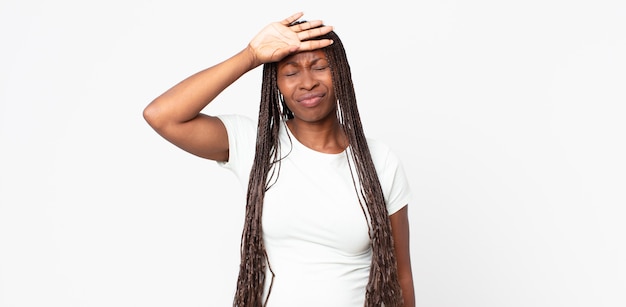 Afro-zwarte volwassen vrouw die er gestrest, moe en gefrustreerd uitziet, het zweet van het voorhoofd droogt, zich hopeloos en uitgeput voelt