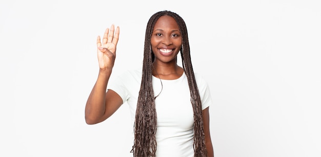 Afro-zwarte volwassen vrouw die lacht en er vriendelijk uitziet, nummer vier of vierde toont met de hand naar voren, aftellend
