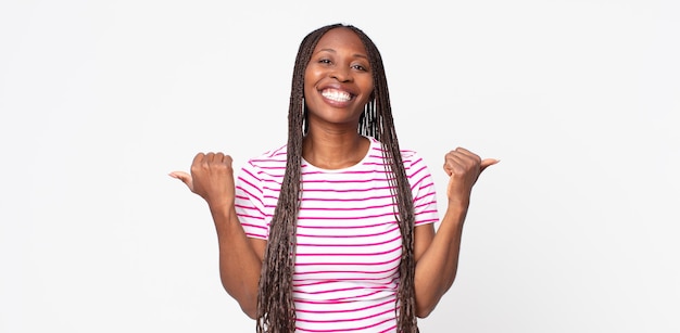 afro zwarte volwassen vrouw die vrolijk lacht en er gelukkig uitziet, zich zorgeloos en positief voelt met beide duimen omhoog