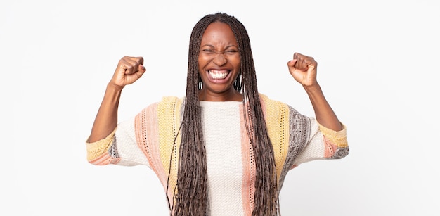 Afro-zwarte volwassen vrouw die zich gelukkig, verrast en trots voelt, schreeuwt en succes viert met een grote glimlach