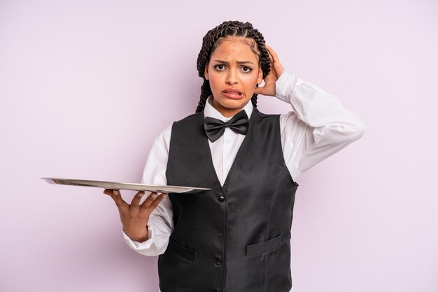 Afro-zwarte vrouw die zich gestrest, angstig of bang voelt, met de handen op het hoofd. ober met een dienblad