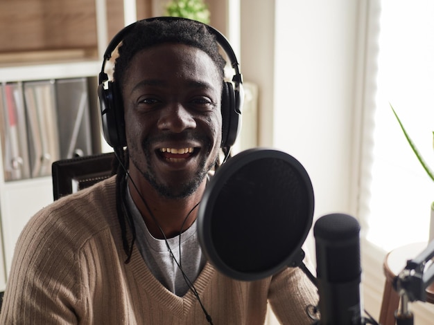 Photo afroamerican happy young male recording audio blog in headphones microphone broadcasting at home