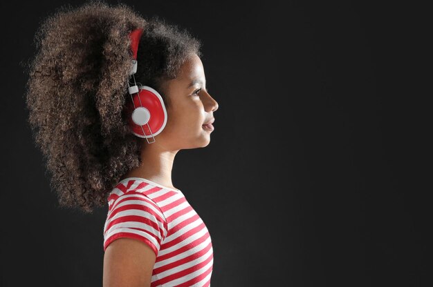 AfroAmerican little girl with headphones on dark background