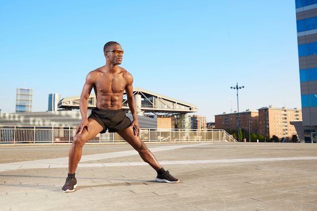 Afroamerican man doing stretching in urban environment