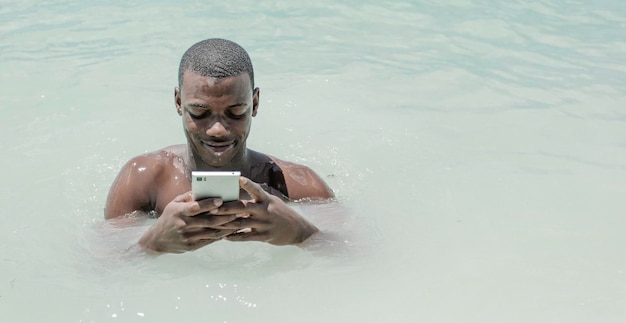 Afroamerican man using a smart phone inside the sea