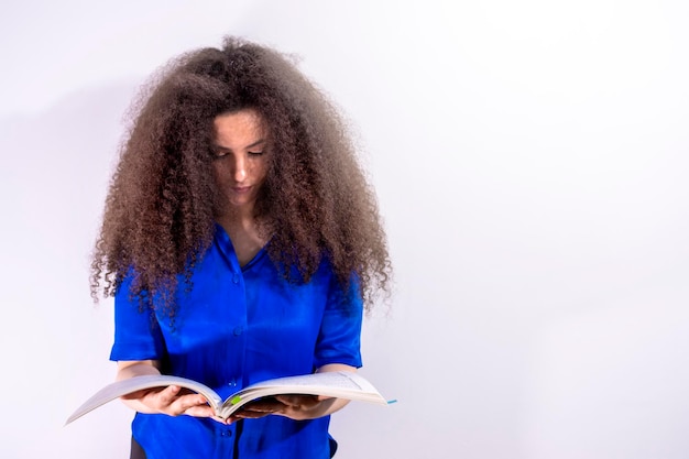 Afrohaired young girl studying a book of sheet music on white background