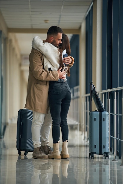 Afscheid nemen, elkaar omhelzen. Het echtpaar is samen in de hal van de luchthaven.