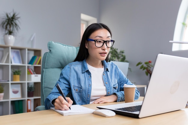 Afstandsonderwijs jonge mooie aziatische vrouwelijke student die een online examen aflegt terwijl hij in een bril zit en