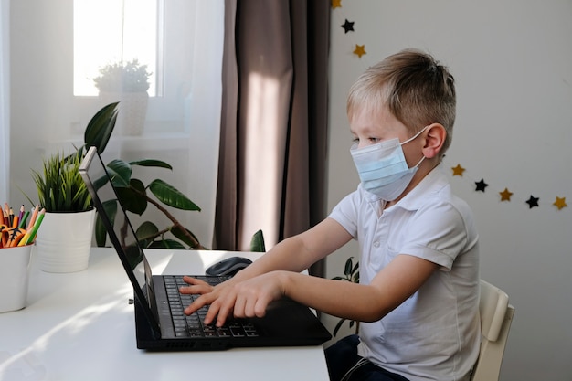 Afstandsonderwijs online onderwijs. Leuke Kaukasische jongen die thuiswerk met laptop thuis doen terwijl quarantaine van het coronavirus van epidemie