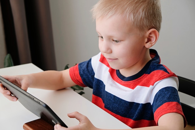 Afstandsonderwijs online onderwijs. Leuke Kaukasische jongen die thuiswerk met tabletpc thuis doet