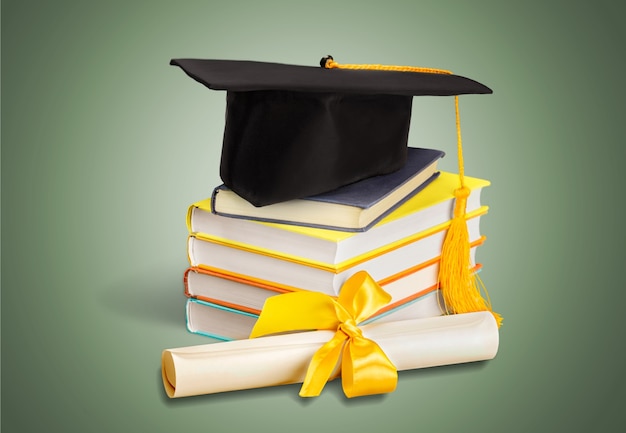 Afstuderen baret bovenop stapel boeken op background