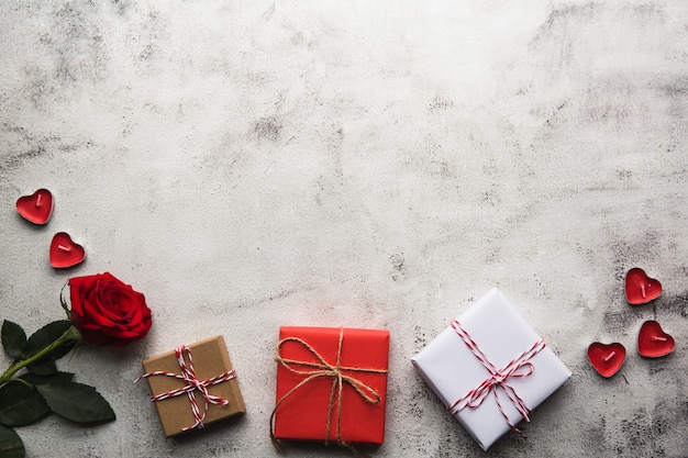 Aftelkalender voor Valentijnsdag, geschenkdoos van kraftpapier met een lint, roos en kaarsen op grijze achtergrond