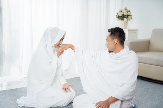 After sholat wife kissing husband's hand wearing white traditional clothes