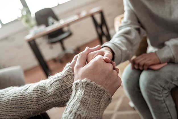 Dopo un discorso sincero. padre che indossa un maglione grigio che stringe la mano a sua figlia dopo un discorso sincero