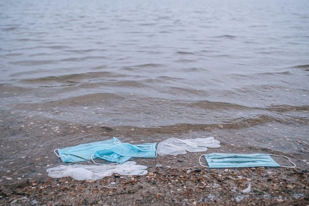 Afval van gebruikte medische maskers en handschoenen op het strand en in het water