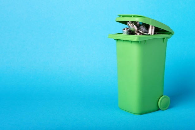 Afvalbatterijen in een plastic container. Recycleren van afval. Milieuconcept. Mand met batterijen op een blauwe achtergrond.