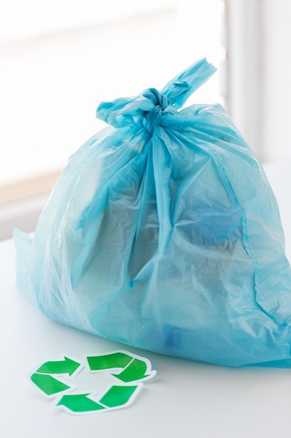 afvalrecycling, hergebruik, afvalverwijdering, milieu en ecologieconcept - close-up van vuilniszak met afval of afval en groen recycle symbool thuis