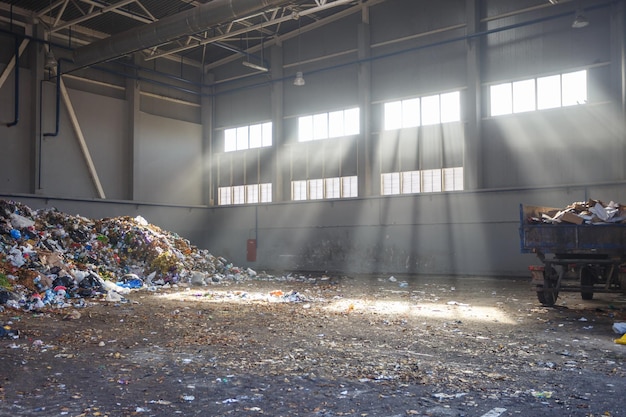 Afvalsorteer- en recyclingwerkplaats met aanhanger bij de afvalverwerkingsfabriek met zonnestralen Gescheiden afvalinzameling Recycling en opslag van afval voor verdere verwijdering