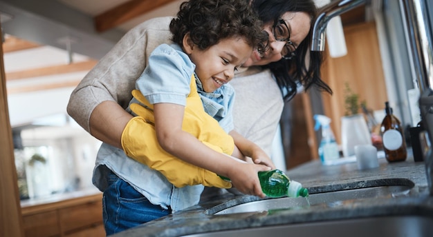 Afwassen en moeder met kind in de keuken om huishoudelijk werk te leren lesgeven en helpen met klusjes Huishouden gelukkig gezin en moeder en jongen met zeep voor het schoonmaken van hygiëne en ontwikkeling