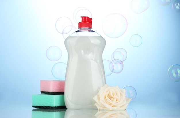 Foto afwasvloeistof met sponzen en bloemen op blauwe achtergrond