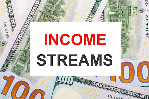 미국 달러를 배경으로 INCOME STREAMS Financial 개념이 있는 흰색 카드