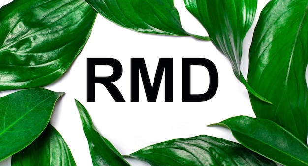 Against the background of green natural leaves a white card with the text RMD Required Minimum Distributions