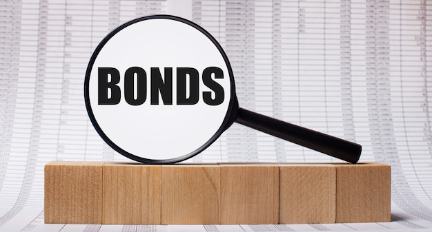 На фоне отчетов о деревянных кубиках - увеличительное стекло с текстом BONDS. Бизнес-концепция