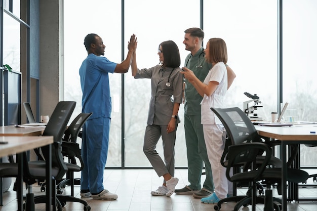 Photo against big panoramic windows group of doctors are together indoors