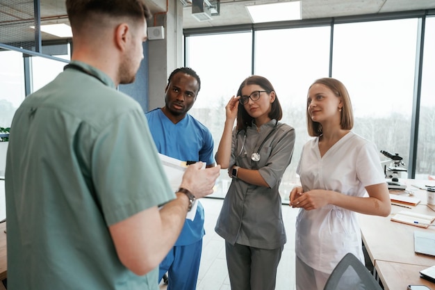 Against big panoramic windows Group of doctors are together indoors