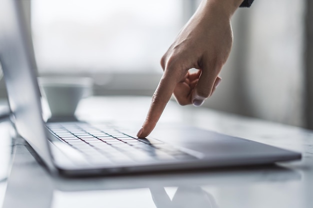 Against a blurred office scene the image details a woman's hands nimbly typing on a trendy laptop keyboard