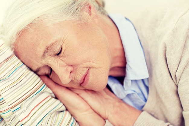 age, relax and people concept - happy senior woman sleeping on pillow at home